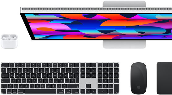 Studio Display ekranı, siyah Magic Keyboard, siyah Magic Mouse, siyah Magic Trackpad ve beyaz AirPods kutusunun yukarıdan görünümü