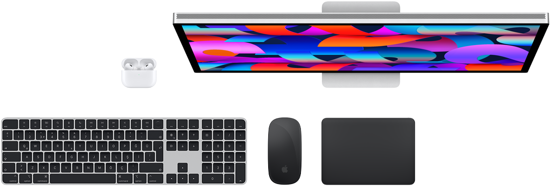 Mac aksesuarlarının üstten görünümü: Studio Display, AirPods, Magic Keyboard, Magic Mouse ve Magic Trackpad